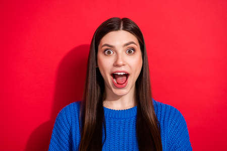 Photo portrait brunette wearing blue sweater staring amazed with opened mouth isolated on vibrant red color backgroundの写真素材
