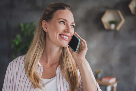 Photo of lovely mature blond lady talk telephone look wear striped shirt at home in free-time apartment aloneの写真素材