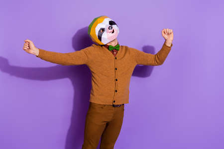 Photo of young sleepy man just waking up stretch arms incognito red panda isolated over violet color backgroundの写真素材