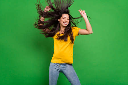 Photo portrait of overjoyed girl with long brunette hair flying wind smiling dancing at party enjoying music isolated vibrant green color backgroundの写真素材