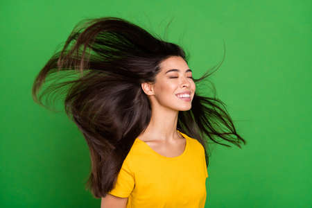 Photo portrait of dreamy girl with long brunette hair flying enjoying wind smiling isolated bright green color background copyspaceの写真素材