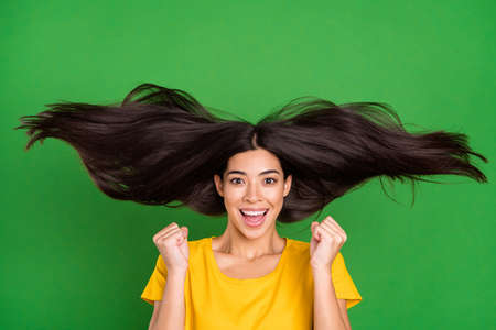 Photo portrait of girl with long brunette hair gesturing like winner smiling overjoyed isolated on bright green color backgroundの写真素材