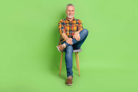Full body photo of funky old beard man sit wear shirt jeans footwear isolated on green color...