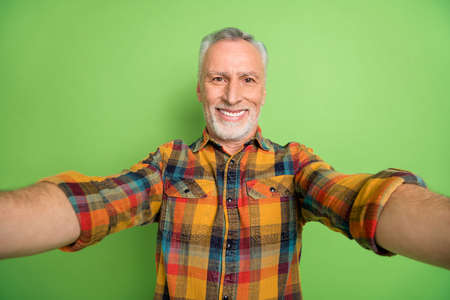 Photo of cute elder beard man do selfie wear yellow shirt isolated on green color backgroundの写真素材