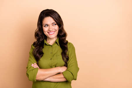 Photo of young charming lady wonder look empty space crossed hands isolated over beige color backgroundの写真素材