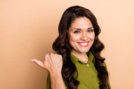 Profile side photo of mature cheerful lady indicate finger empty space ads promo suggest isolated over beige color backgroundの写真素材