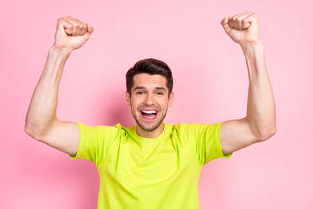 Photo portrait happy brunet man wearing bright t-shirt overjoyed gesturing like winner isolated pastel pink color backgroundの写真素材