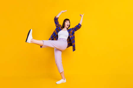 Full length body size view of pretty cheery funky girl dancing having fun good mood fooling isolated over bright yellow color backgroundの写真素材