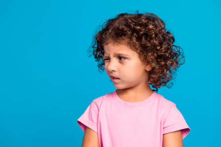 Portrait of attractive suspicious wavy-haired girl winking looking aside copy space isolated over vibrant blue color backgroundの写真素材