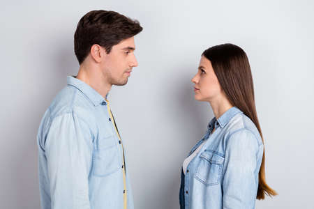 Photo of serious confident brother sister wear jeans shirts looking eyes to eyes isolated grey color backgroundの写真素材