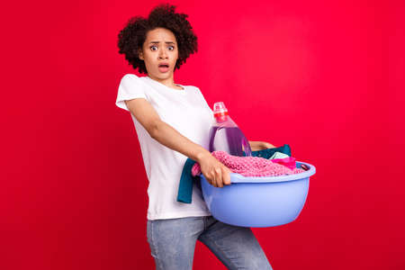 Photo portrait housewife amazed keeping bowl of dirty clothes do cleaning isolated vibrant red color backgroundの写真素材