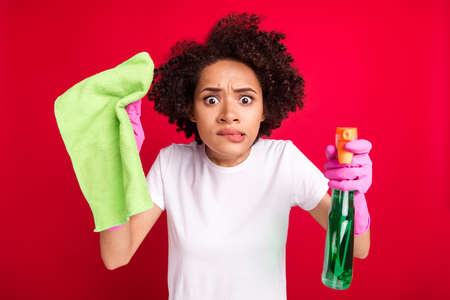 Photo portrait woman biting lip amazed wearing gloves polishing dust isolated vibrant red color backgroundの写真素材