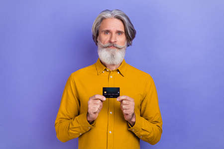 Photo of aged man hold bank card advertise profit recommend decision isolated over purple color backgroundの写真素材