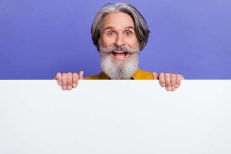 Portrait of attractive cheerful gray-haired man showing copy empty space ad isolated over bright violet purple color backgroundの写真素材