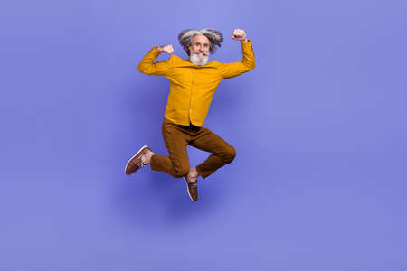 Full length body size view of attractive cheery strong gray-haired man jumping striving isolated over bright violet purple color backgroundの写真素材