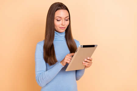 Photo of pretty calm young lady hold use tablet finger touch screen isolated on beige color backgroundの写真素材
