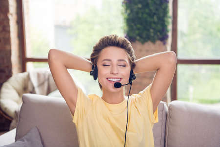 Photo of pretty relaxed dreamy secretary lady enjoy rest hands head wear headset yellow t-shirt in...