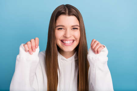 Photo portrait girl in white hoody smiling overjoyed gesturing like winner isolated pastel blue...
