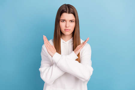 Photo portrait girl in white hoody unhappy with crossed hands showing stop isolated pastel blue color backgroundの写真素材