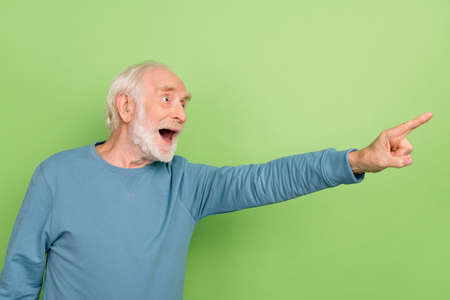 Photo of cool old beard man index promo wear blue sweater isolated on green color backgroundの写真素材