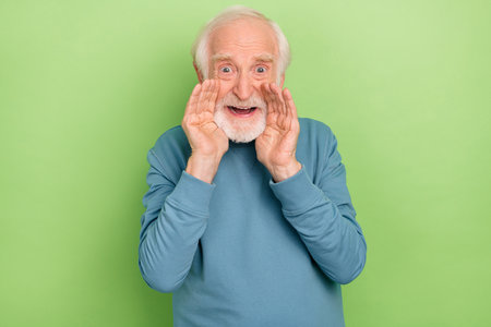 Portrait of funky aged person arms near open mouth say shout news isolated on green color backgroundの写真素材