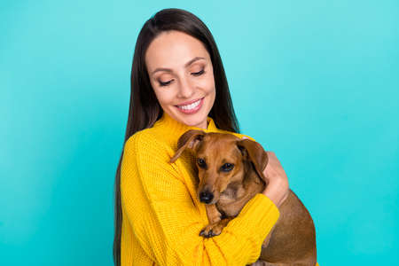 Portrait of attractive cheerful sweet careful girl owner holding in hands dog isolated over bright...