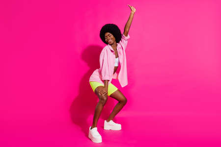 Photo of pretty charming dark skin lady wear casual shirt dancing twerk smiling isolated pink color backgroundの写真素材