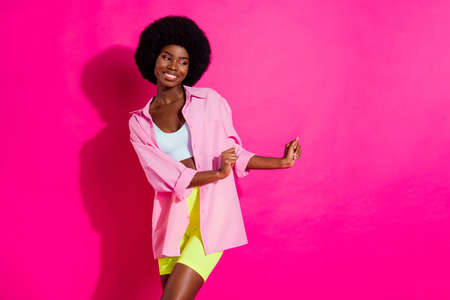 Photo of sweet cute dark skin lady wear casual shirt dancing looking empty space smiling isolated pink color backgroundの写真素材