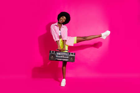 Photo of charming sweet dark skin woman dressed crop top smiling dancing listening boombox isolated pink color backgroundの写真素材
