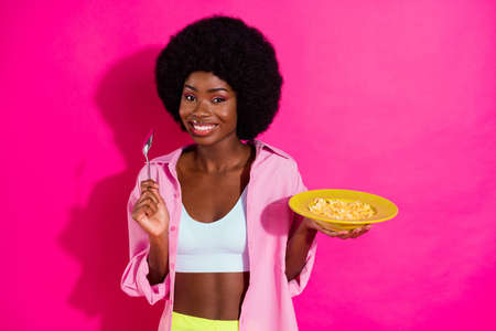 Photo of charming cute dark skin woman dressed crop top smiling ready eat cornflakes isolated pink color backgroundの写真素材