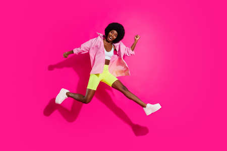 Full length body size view of lovely slender cheerful girl jumping running having fun isolated over bright magenta fuchsia color backgroundの写真素材