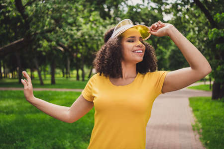 Portrait of attractive brunette dreamy cheerful girl touching cap resting enjoying free time at forest outdoorの写真素材