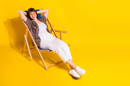 Full length photo of rest lady sit relax wear eyewear shirt trousers isolated on yellow color...