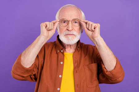 Photo of strict aged man hands eyewear wearing brown shirt isolated over purple color backgroundの写真素材