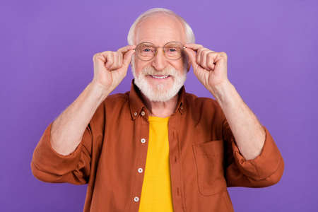 Photo of optimistic old man hands glasses wearing brown shirt isolated over purple color backgroundの写真素材