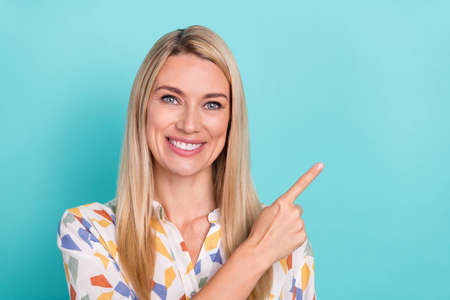 Photo of nice young blond lady index empty space wear white blouse isolated on turquoise color...