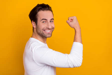 Profile portrait of satisfied glad person beaming smile arm showing biceps isolated on yellow color...