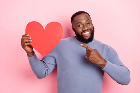 Photo of positive guy direct finger heart symbol toothy smile wear grey shirt isolated pink color backgroundの写真素材