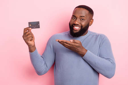 Photo of reliable promoter man palm presenting debit card option wear grey shirt isolated pink color backgroundの写真素材