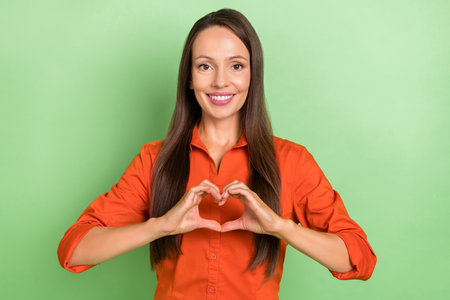 Photo of young cheerful woman show hands small heart symbol romantic isolated over green color backgroundの写真素材