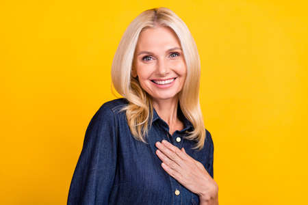 Photo of shiny pretty lady pensioner dressed denim outfit smiling arm chest isolated yellow color...