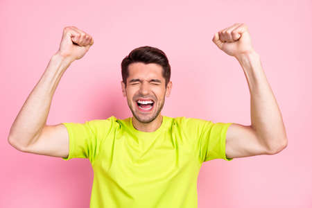 Photo portrait shouting brunet man wearing bright t-shirt amazed gesturing like winner isolated...