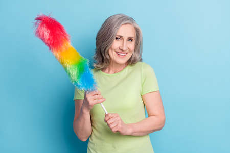 Photo of positive cheerful old woman hold hands duster good mood smile isolated on blue color backgroundの写真素材