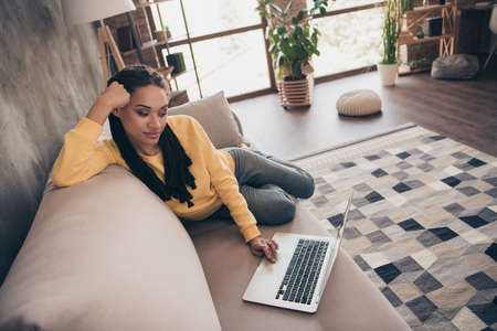 Photo of pretty charming young lady wear yellow pullover sitting couch working modern gadget indoors...