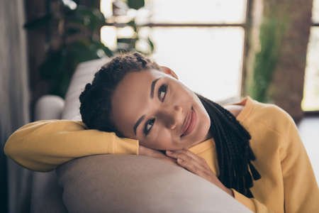 Photo of dreamy cute young woman dressed yellow sweater lying sofa smiling indoors home roomの写真素材