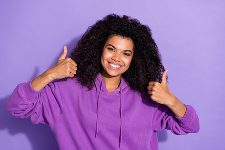 Photo of pretty positive person two hands show thumb up beaming smile isolated on purple color backgroundの写真素材