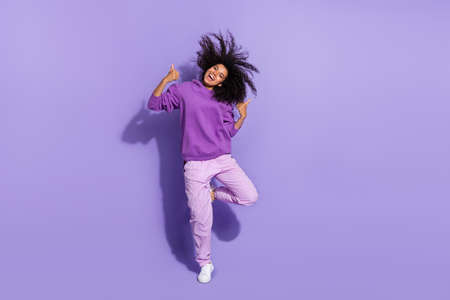Full length photo of excited crazy pretty lady two hands show thumb up flying curly hairdo isolated on purple color backgroundの写真素材