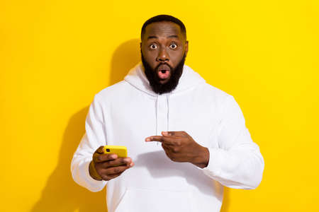 Photo of cool millennial beard man indicate telephone wear white hoodie isolated on yellow color...