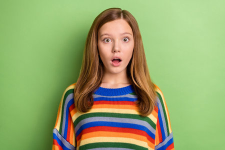 Portrait of attractive amazed funny girly girl incredible news reaction isolated over bright green color backgroundの写真素材
