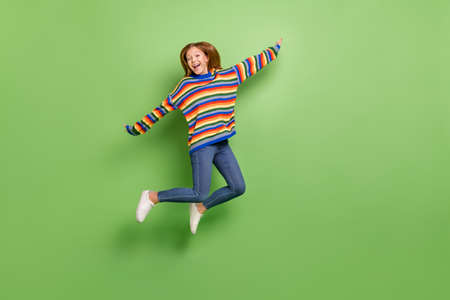 Full length body size view of attractive funky carefree cheerful girl jumping having fun isolated over bright green color backgroundの写真素材